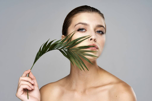 Young beautiful model posing with leaf in studio - Foto, imagen