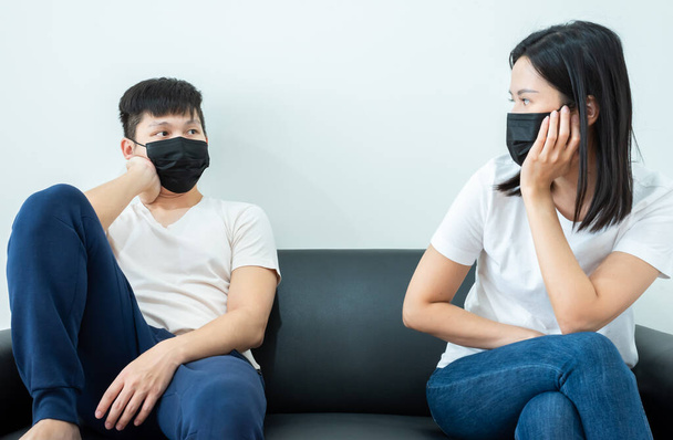 An Asian couple wearing a black mask and stays together with boring and social distancing. - Foto, Imagem