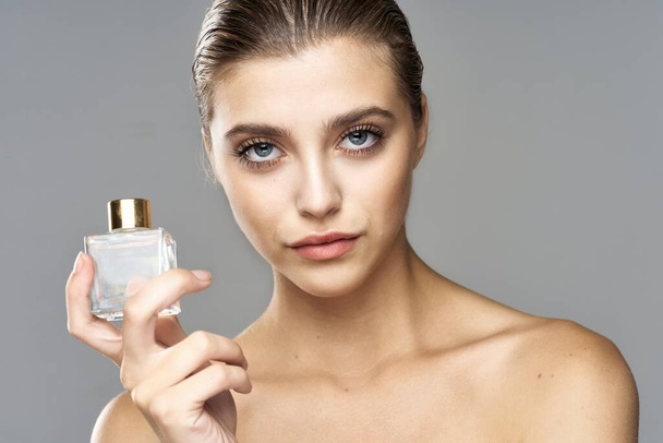 Parfüm şişeli güzel bir kadının portresi. Stüdyo çekimi.   - Fotoğraf, Görsel