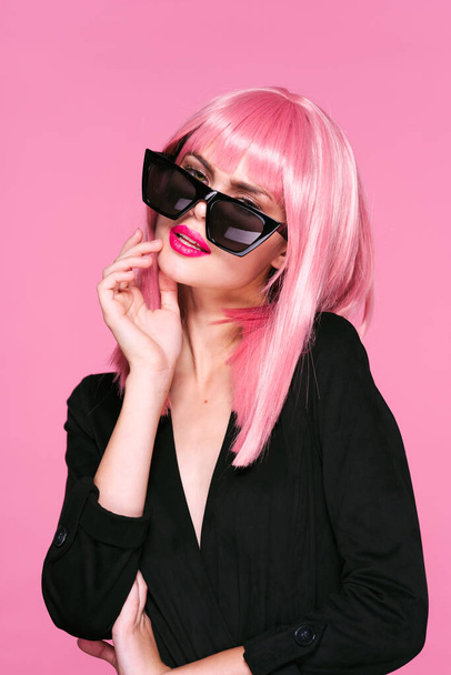 young beautiful woman in pink wig and sunglasses posing in studio  - 写真・画像
