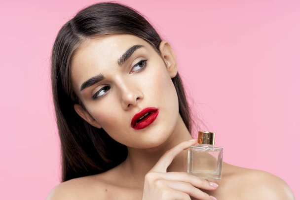 Portrait of young beautiful woman with  red lipstick on her lips holding perfume bottle. Beauty, fashion photography  - Fotoğraf, Görsel