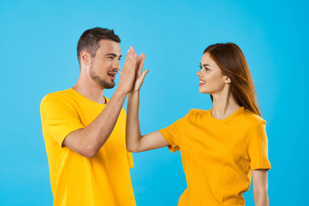 young  handsome man and woman giving high five  in studio  on blue background  - Fotó, kép