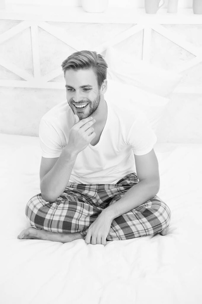 start day smiling. Menswear pajamas for home relax. male full of energy. happy man sit in pajama. man relax in bed. perfect morning. guy touch his unshaven beard. feeling cosy and comfortable - Фото, зображення