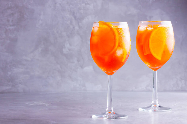 Koktajl Aperol spritz na szarym tle. Dwie szklanki aperolu spritz z pomarańczową plastrami. Letni koktajl w szkle. Przestrzeń kopiowania - Zdjęcie, obraz