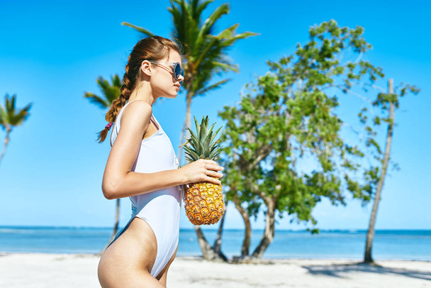 Een vrouw in een wit badpak met ananas. Hoge kwaliteit foto - Foto, afbeelding