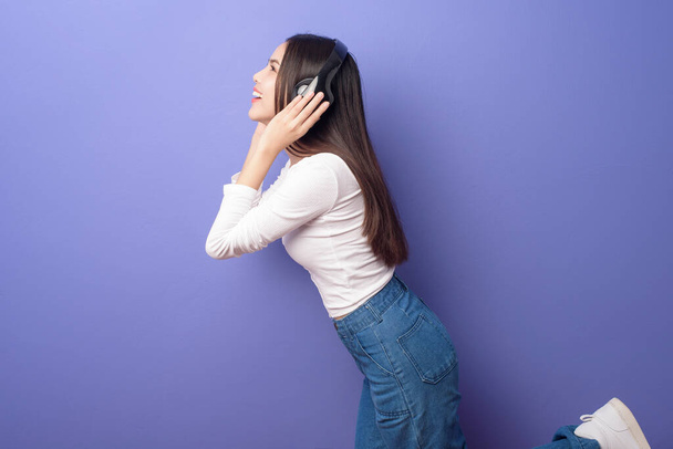 Young woman is listening to music  on purple background  - Fotó, kép