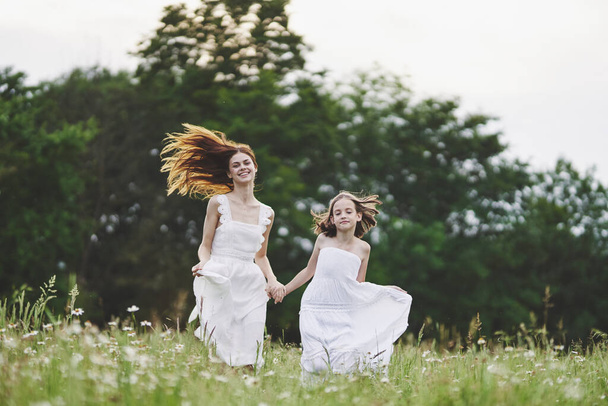 Young mother and her daughter having fun on camomile field - Foto, Bild