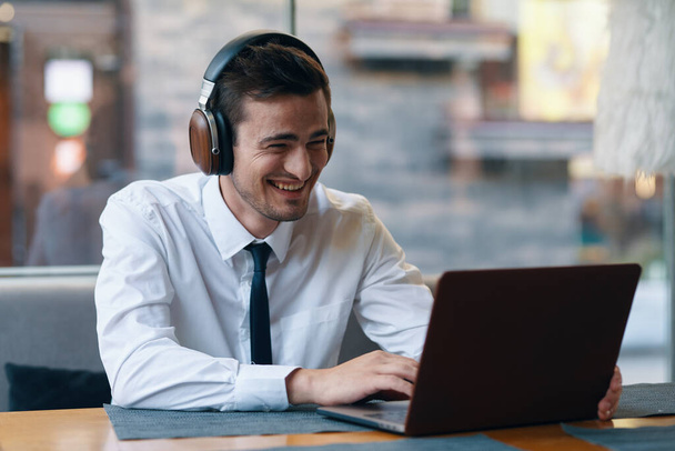 Joven hombre de negocios guapo en los auriculares que trabajan con el ordenador portátil en la oficina  - Foto, imagen