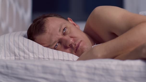 Egy férfi fekszik az ágyban késő éjjel, és nem tud elaludni. - Felvétel, videó