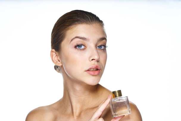 Egy fiatal, gyönyörű nő arcképe parfümös üveggel. Stúdió felvétel.   - Fotó, kép