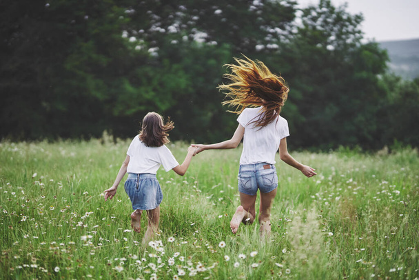Young mother and her daughter having fun on camomile field - Foto, Imagem
