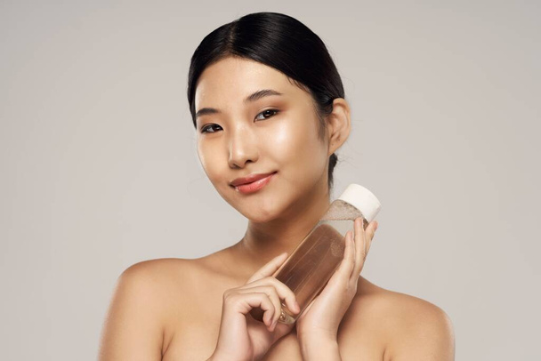 Studio shot. Portrait of young asian woman with beauty product - Fotografie, Obrázek