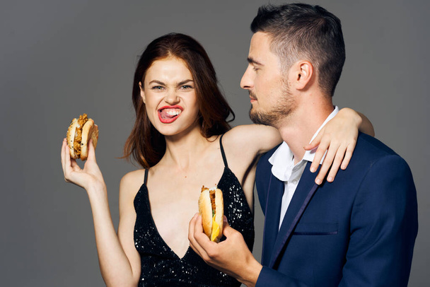 Young beautiful couple eating hamburgers. Studio shot - Photo, Image