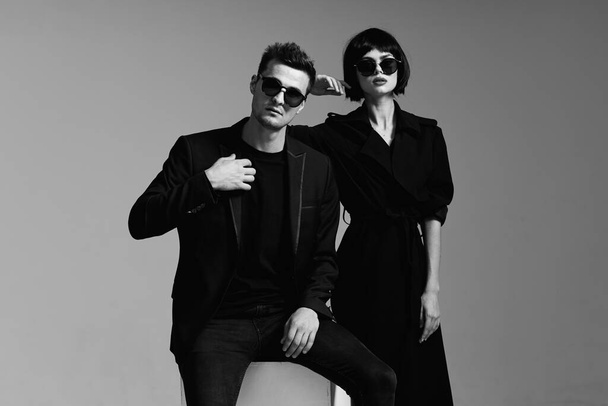 Jeune beau couple en lunettes de soleil posant en studio. Noir et blanc.    - Photo, image