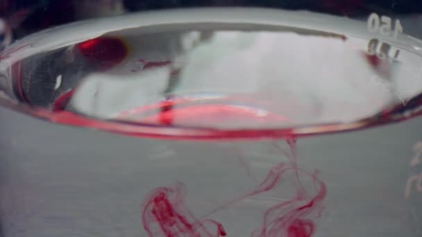 Vörös folyadék csepeg a flaskába. Vízben folyó vércseppek - Felvétel, videó