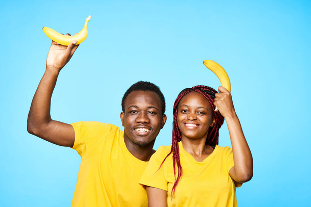 uomo e donna di aspetto africano che tengono banane su sfondo isolato - Foto, immagini