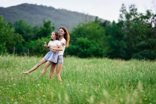Молодая мать и ее дочь веселятся на ромашковом поле - Фото, изображение