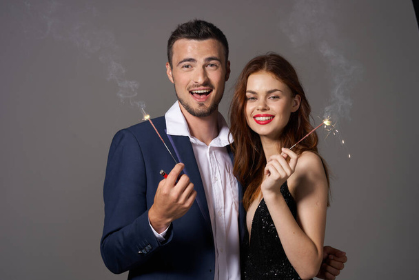 portrait de jeune beau couple célébrant le nouvel an avec des étincelles  - Photo, image