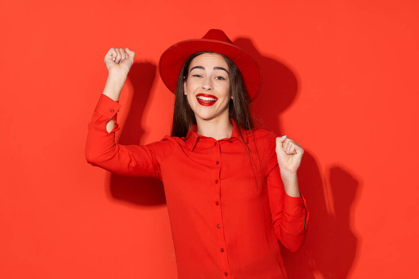 Студийный снимок Молодая красивая счастливая женщина в красном на красном фоне
 - Фото, изображение