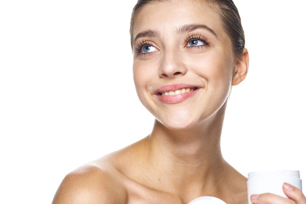 Studio shot of young beautiful woman with cream, beauty product on an isolated background - Photo, image
