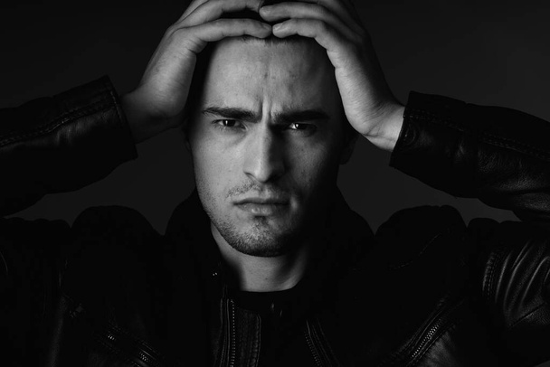 Studio shot of young handsome man with headache  in studio. Black and white   - Фото, изображение