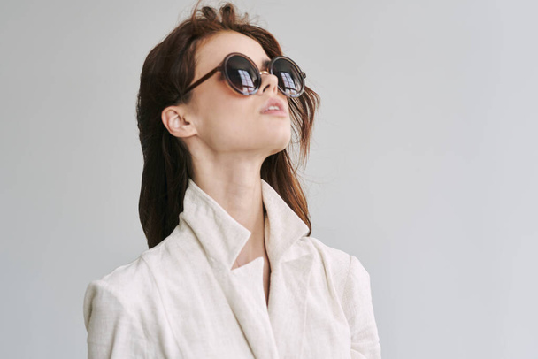 молода красива жінка в сонцезахисних окулярах позує в студії
   - Фото, зображення