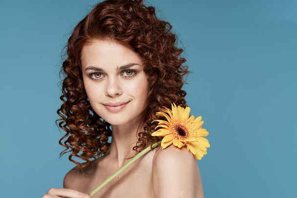 Young woman with flower posing in studio - Valokuva, kuva