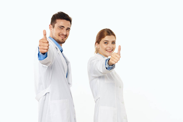 Jovens médicos em estúdio mostrando polegares para cima, fundo isolado.  - Foto, Imagem