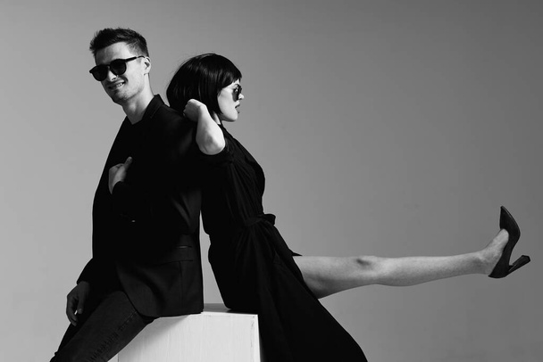 Young beautiful couple in sunglasses posing in studio. Black and white.    - Фото, зображення