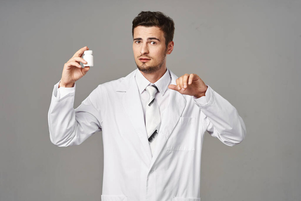 Студийный снимок Молодой врач показывает таблетки на изолированном фоне  - Фото, изображение