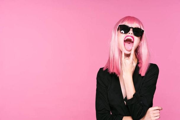 Giovane donna in parrucca rosa gesticolando su sfondo rosa - Foto, immagini
