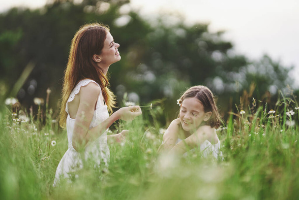 Young mother and her daughter having fun on camomile field - Foto, Imagen