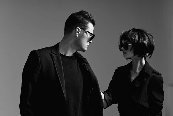 Joven hermosa pareja en gafas de sol posando en el estudio. Blanco y negro
.    - Foto, Imagen