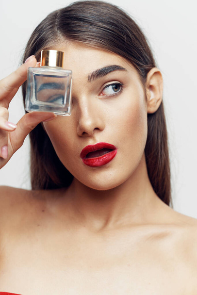 Young beautiful woman holding perfume bottle in studio - Foto, Bild