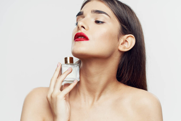 Beyaz arka planda parfüm şişesi olan güzel bir kadının portresi. - Fotoğraf, Görsel