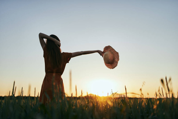 Fiatal nő pózol a búzamezőn naplementekor - Fotó, kép