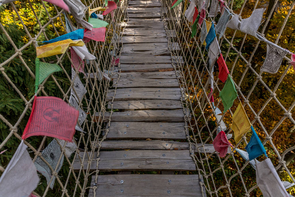 Himalajski chodnik głęboko w naturze Skywalk drewniana konstrukcja przełęczy uderzająca o silne pnie drzew wiatrowych kolorowe flagi podczas słonecznego jesiennego dnia zdobytego w rejonie Radhost Pustevny - Zdjęcie, obraz