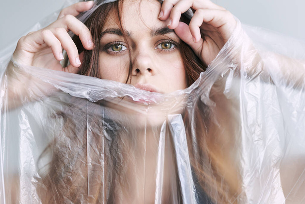 young woman tearing plastic, polyethylene - 写真・画像