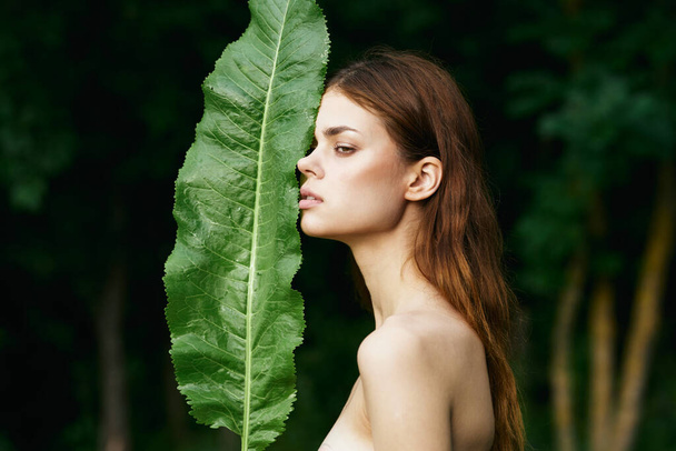 Young beautiful woman posing  with  leaf outdoors - Photo, Image