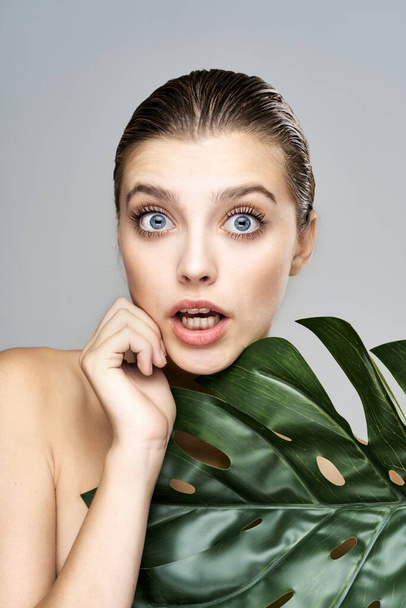 Young beautiful model posing with leaf in studio - Photo, image