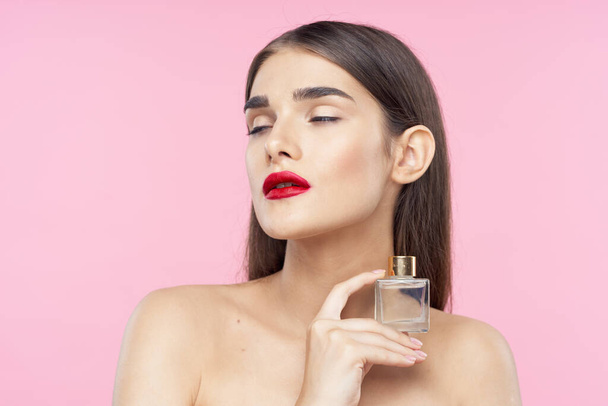 Portret van een mooie jonge vrouw met rode lippenstift op haar lippen met parfumflesje. Schoonheid, mode fotografie  - Foto, afbeelding