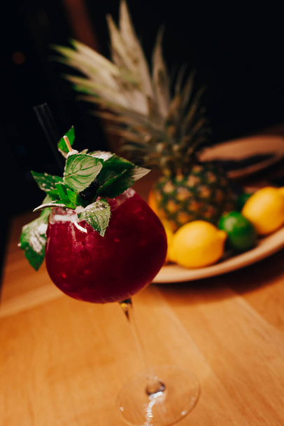 Fresh Cherry summer Author inspired Cocktail Drink - on bar counter on Pineapple fruit Achtergrond. Close-up Bovenaanzicht. Kopieer plakruimte voor design mensen en luxe service barman in nachtclub - Foto, afbeelding