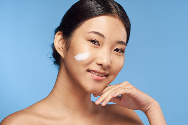Young asian woman applying moisturizer on her face  - 写真・画像