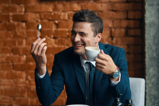 Jonge gelukkige zakenman met koffiekop op kantoor  - Foto, afbeelding