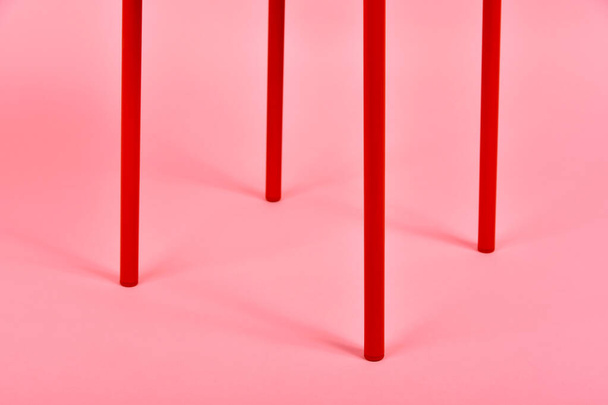 ミニマルなインテリアスタイル、パステルピンクの背景に赤い金属製の椅子脚の詳細、ミニマリズム家具. - 写真・画像