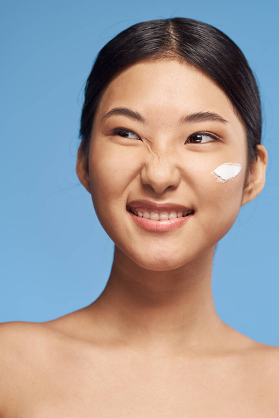 Joven mujer asiática aplicando crema hidratante en su cara
  - Foto, Imagen