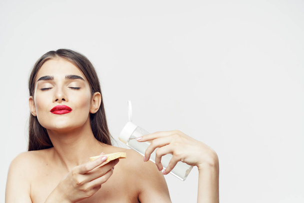 Young beautiful woman cleaning her face with sponge. Beauty routine. Studio shot - Foto, imagen