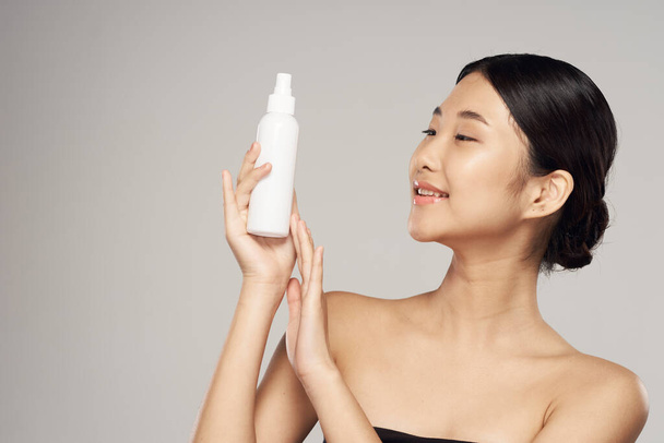 Студийный снимок Портрет молодой азиатки с косметическим продуктом
 - Фото, изображение