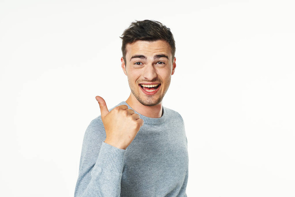 jonge knappe man tonen duim omhoog geïsoleerd op witte achtergrond  - Foto, afbeelding