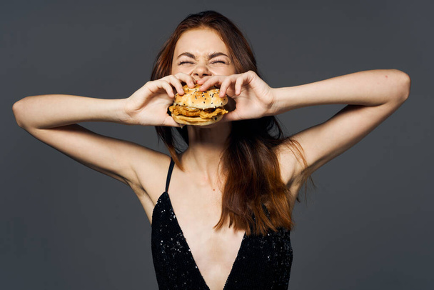 Молодая красивая женщина с гамбургером. Снимок студии - Фото, изображение